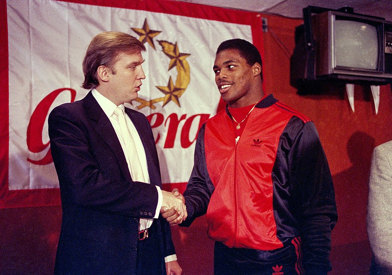 AP photo by Dave Pickoff / New Jersey Generals owner Donald Trump shakes hands with Herschel Walker in New York on March 8, 1984, after the former Georgia Bulldogs running back agreed to a four-year contract with the USFL team. Another incarnation of the USFL will debut this weekend, the latest attempt to make professional football in the spring work.