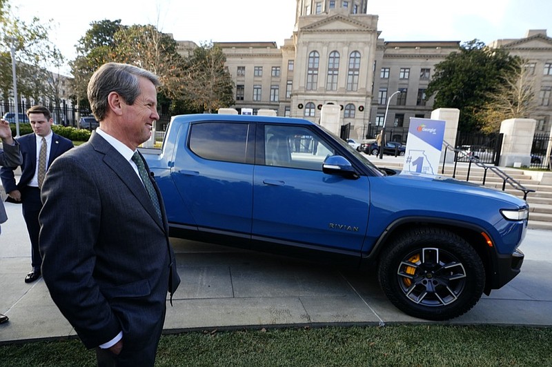 Gov. Brian Kemp stands next to a Rivian electric truck while announcing the company's plans to build a $5 billion plant east of Atlanta projected to employ 7,500 workers, Thursday, Dec. 16, 2021, in Atlanta. Some residents oppose the plant, saying it will spoil their rural quality of life. (AP Photo/John Bazemore, File)
