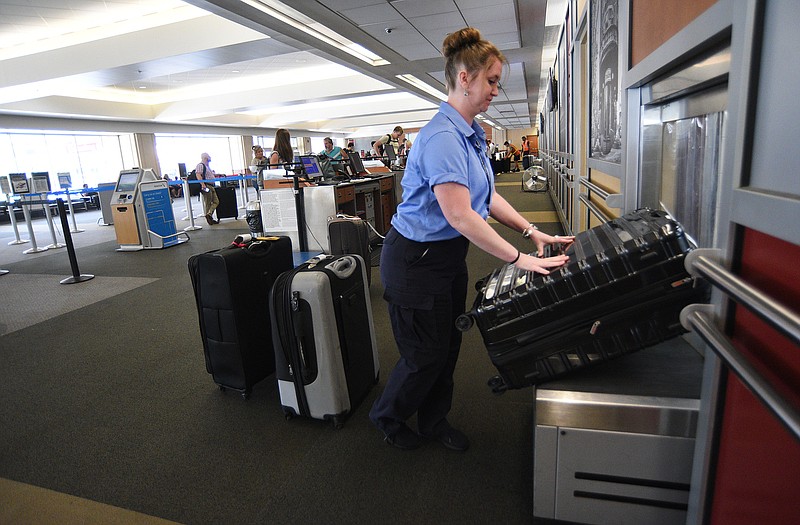 Staff photo by Matt Hamilton / Customer service agent Candace Russell loads suitcases on a conveyer belt at the Chattanooga Airport on Friday, July 1, 2022.
