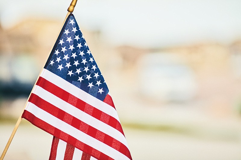 Vibrant American flag in summer sunshine with defocused street - stock photo flag july 4 tile road / Getty Images
