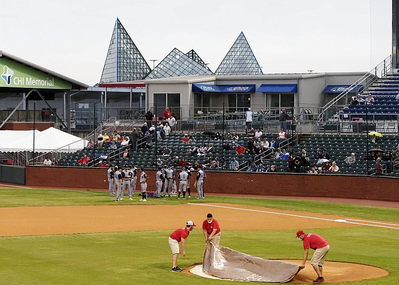 Staff photo / Members of the grounds crew cover up the pitching mound on opening day at AT&T Field on Tuesday, May 4, 2021, in Chattanooga, Tenn. The Chattanooga Lookouts were slated to open their season against the Rocket City Trash Pandas, however, inclement weather forced the game to be postponed.