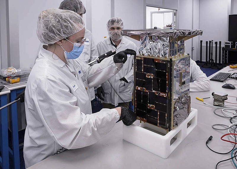 Rebecca Rogers, systems engineer, left, takes dimension measurements of the CAPSTONE spacecraft in April 2022, at Tyvak Nano-Satellite Systems, Inc., in Irvine, Calif. (Dominic Hart/NASA via AP)


