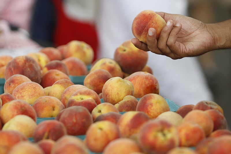 Staff file photo / A customer examines the produce at the 2010 Peach Festival at Chattanooga Market. This year's festival is Sunday at First Horizon Pavilion.