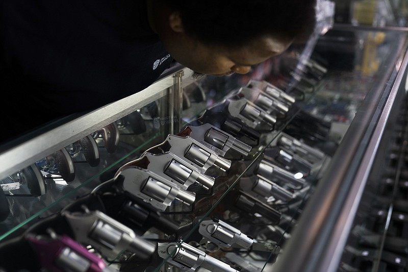 File photo by Jae C. Hong if The Associated Press / Sales associate Elsworth Andrews arranges guns on display at Burbank Ammo & Guns in Burbank, Calif., on June 23, 2022. The Supreme Court ruled that Americans have a right to carry firearms in public for self-defense, a major expansion of gun rights.