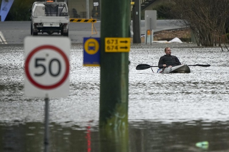 A man paddles his kayak through a flooded street at Windsor on the outskirts of Sydney, Australia, Tuesday, July 5, 2022. Hundreds of homes have been inundated in and around Australia's largest city in a flood emergency that was impacting 50,000 people, officials said Tuesday. (AP Photo/Mark Baker)