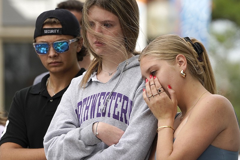 Helena Kavanaugh, right, stands with friends Addison Schwan, center, and Charlie Shookman after Kavanaugh placed flowers at a memorial for the seven people who lost their lives in the Highland Park, Ill., Fourth of July mass shooting, Wednesday, July 6, 2022, in Highland Park. (AP Photo/Charles Rex Arbogast)