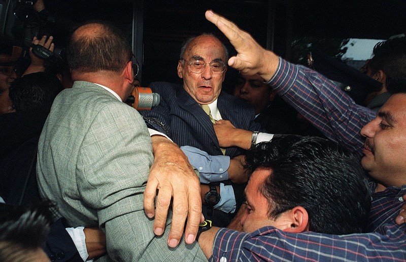 Former Mexican President Luis Echeverria, center, leaves the prosecutors' office surrounded by bodyguards in Mexico City, July 9, 2002. Echeverria, blamed for some of Mexico's worst political killings of the 20th century, has died at the age of 100, current President Andres Manuel Lopez Obrador confirmed Saturday, July 9, 2022. (AP Photo/Marco Ugarte, File)