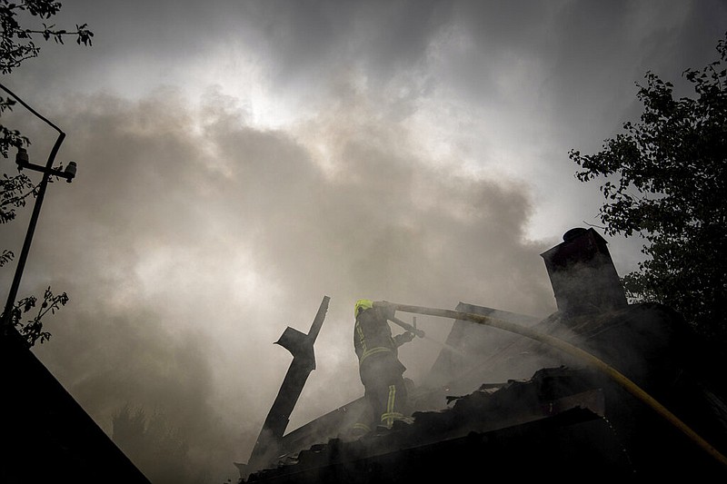 A rescue worker puts out the fire on a destroyed house after a Russian attack in a residential neighborhood in downtown Kharkiv, Ukraine, on Monday, July 11, 2022. The top official in the Kharkiv region said Monday the Russian forces launched three missile strikes on the city targeting a school, a residential building and warehouse facilities. (AP Photo/Evgeniy Maloletka)