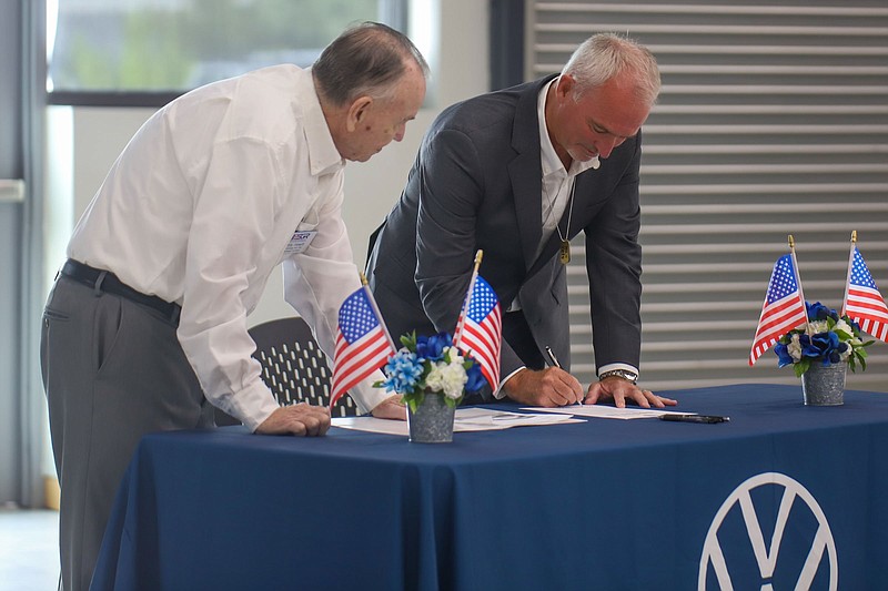 Staff photo by Olivia Ross / Volkswagen Chattanooga CEO Chris Glover, right, signs a document Tuesday alongside Bill Hewitt of the Employer Support of the Guard and Reserves program.