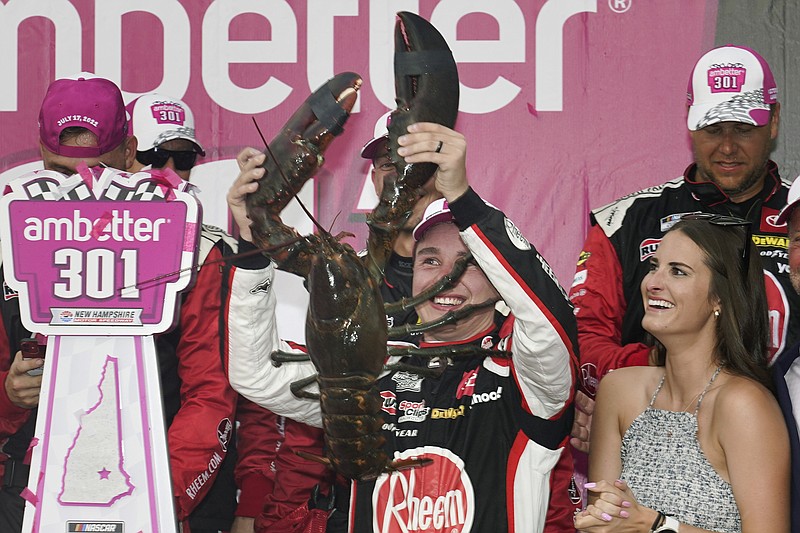 AP photo by Charles Krupa / Joe Gibbs Racing driver Christopher Bell holds up his giant lobster prize as the winner of Sunday's NASCAR Cup Series race while celebrating with his wife, Morgan, right, at New Hampshire Motor Speedway in Loudon.