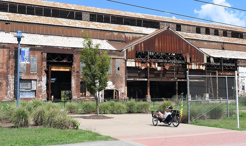 Staff Photo by Robin Rudd / A recumbent cyclist uses the Tennessee Riverwalk as he passes the former Wheland Foundry on July 14. The site is proposed for a redevelopment on the Southside including a stadium for the Chattanooga Lookouts.