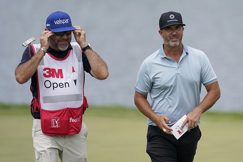 Scott Piercy, right, and his caddie walk up onto the 14th green during the second round of the 3M Open golf tournament at the Tournament Players Club in Blaine, Minn., Friday, July 22, 2022. (AP Photo/Abbie Parr)