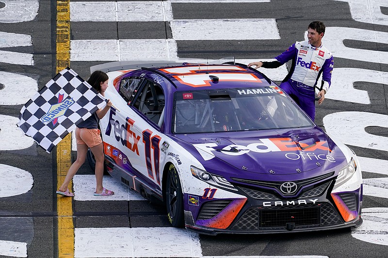 Taylor James Hamlin, left, carries the checkered flag with her dad, Denny Hamlin, after he won a NASCAR Cup Series auto race at Pocono Raceway, Sunday, July 24, 2022, in Long Pond, Pa. NASCAR stripped Hamlin of his win when his No. 11 Toyota failed inspection and was disqualified, awarding Chase Elliott the Cup Series victory. (AP Photo/Matt Slocum)