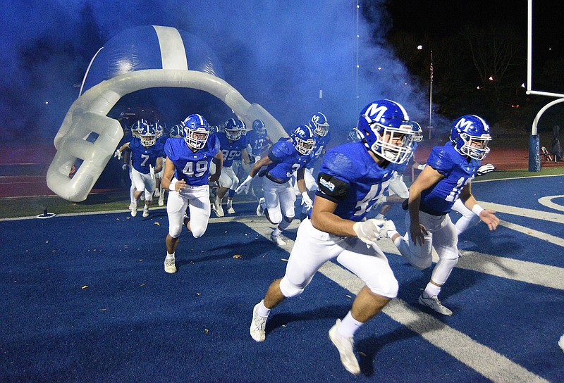 Staff photo by Matt Hamilton / McCallie football players take the field in a cloud of blue smoke before a home game in November 2021.