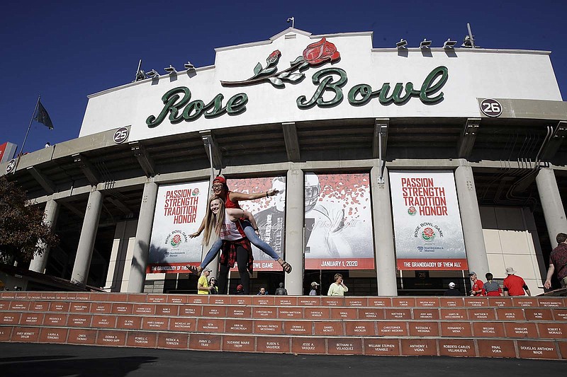 AP photo by Marcio Jose Sanchez / Fans pose for a picture before the Rose Bowl Game on Jan. 1, 2020, in Pasadena, Calif. While the College Football Playoff has somewhat disrupted the tradition of pairing teams from the Big Ten and Pac-12 for the bowl matchup known as the "Grandaddy of Them All," it could truly be left behind in a time of rapid change for the sport.