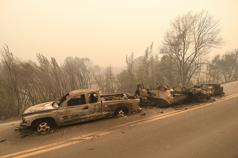 A pickup truck and a trailer that burned overnight in the middle of state Highway 96 are seen destroyed by the McKinney Fire in the community of Klamath River, Calif., Saturday, July 30, 2022. (Scott Stoddard/Grants Pass Daily Courier via AP)