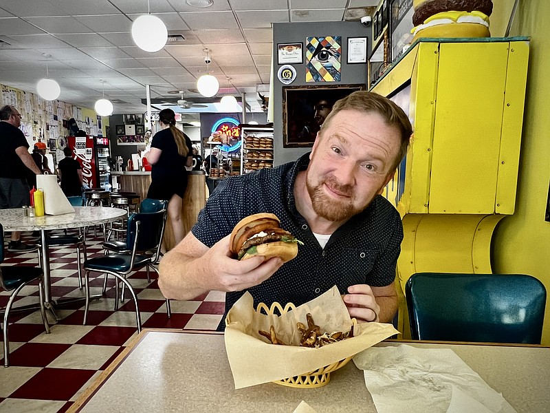 Contributed Photo by Diane Casanova / Former Chattanoogan John Martin, the new evening anchor at KULR 8 News in Billings, Mont., tries a Best of the Bash burger at The Burger Dive in Billings, one of 27 stops on a Burger Trail through the southeastern part of the state.