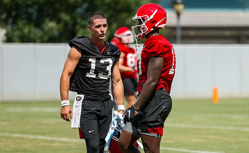 Georgia photo by Tony Walsh / Georgia Bulldogs quarterback Stetson Bennett, displaying his new buzz cut, visits with receiver Kearis Jackson during Thursday afternoon's first preseason practice for the reigning national champions.