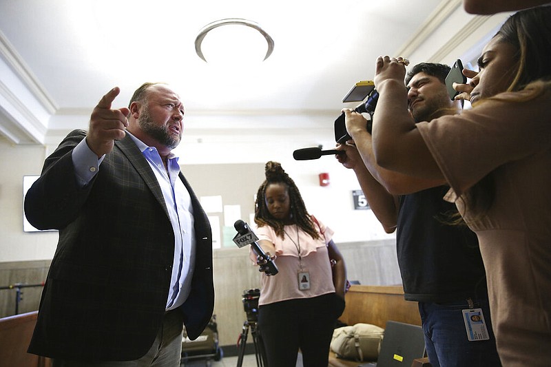 Alex Jones talks to media during a midday break during the trial at the Travis County Courthouse in Austin, Texas, Tuesday, July 26, 2022. An attorney for the parents of one of the children who were killed in the Sandy Hook Elementary School shooting told jurors that Jones repeatedly "lied and attacked the parents of murdered children" when he told his Infowars audience that the 2012 attack was a hoax. Attorney Mark Bankston said during his opening statement to determine damages against Jones that Jones created a "massive campaign of lies" and recruited "wild extremists from the fringes of the internet ... who were as cruel as Mr. Jones wanted them to be" to the victims' families. Jones later blasted the case, calling it a "show trial" and an assault on the First Amendment. (Briana Sanchez/Austin American-Statesman via AP, Pool)
