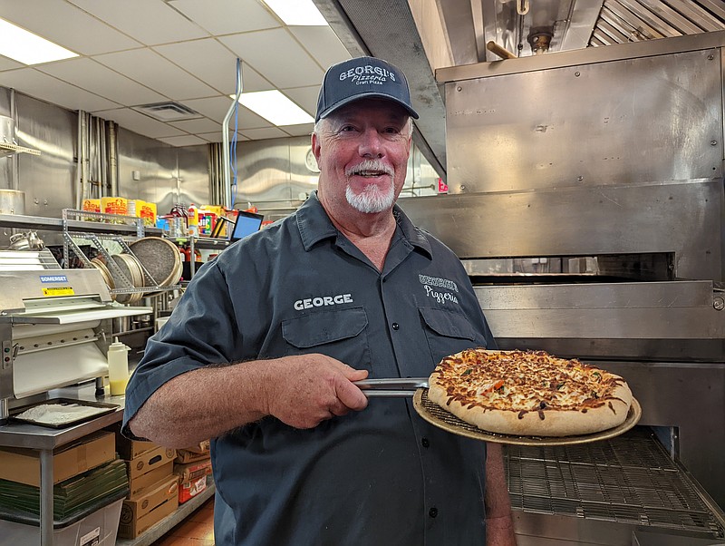 Staff Photo by Tierra Hayes / George Foster pulls a pizza out of the oven on Aug. 9. His restaurant, Georgi's Pizzeria, opened in July.