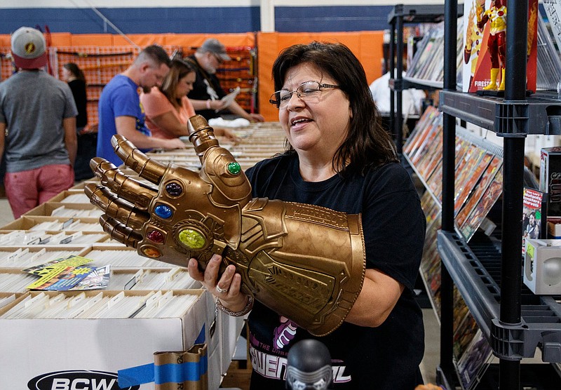 Staff Photo / Debra Hinton demonstrates how to use the gauntlet of the Marvel character Thanos at the Spinner Rack booth during the 2018 FarleyCon toy and comic book expo at the East Ridge Community Center.