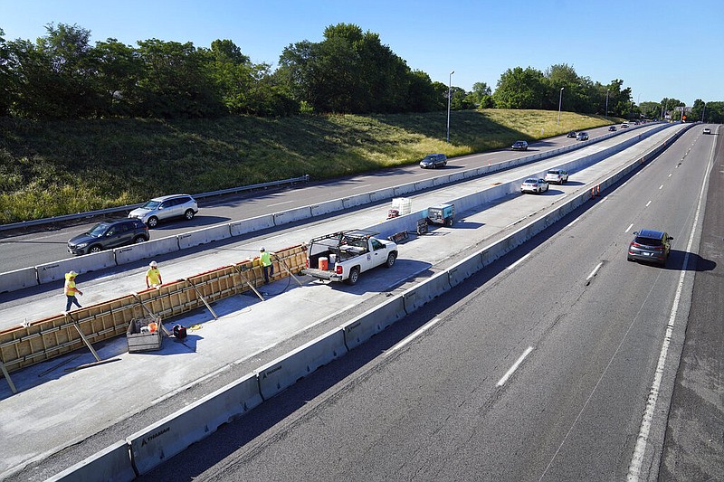 Traffic flows past workers in a construction zone along Interstate 55 in St. Louis, June 9, 2022. United States transportation officials announced $2.2 billion for local infrastructure projects on Thursday, Aug. 11, 2022, paving the way for new bicycle lanes, bridges, roads, railways and ports in scores of communities across the country. (AP Photo/Jeff Roberson, File)