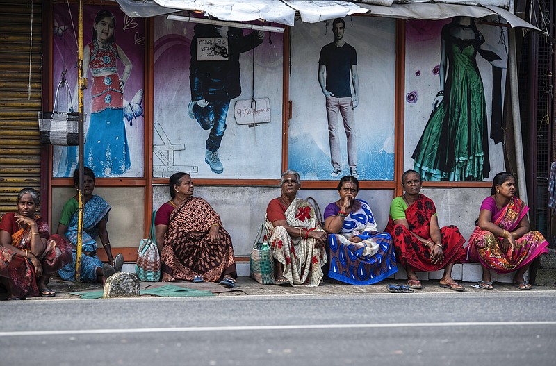 Tamil women sit by a roadside in the morning in anticipation of being hired for daily wage jobs in Kochi, southern Kerala state, India, Wednesday, Aug. 10, 2022. Scenes like this are an everyday reality for millions of Indians, the most visible signs of economic distress in a country where raging unemployment is worsening insecurity and inequality between the rich and poor. (AP Photo/R S Iyer)