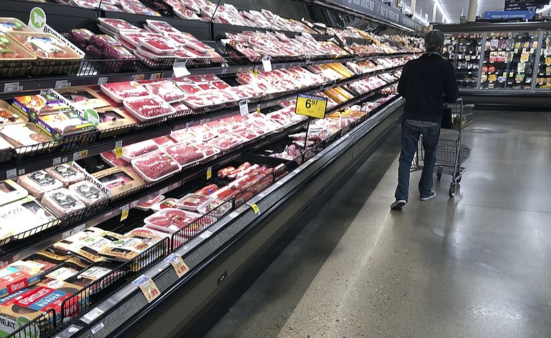 In this May 10, 2020 file photo, a shopper pushes his cart past a display of packaged meat in a grocery store in southeast Denver. (AP Photo/David Zalubowski, File)